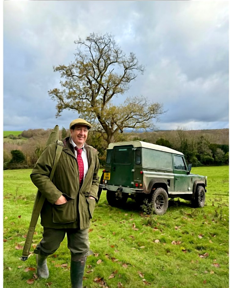 A shooter with a Land Rover Defender in a field